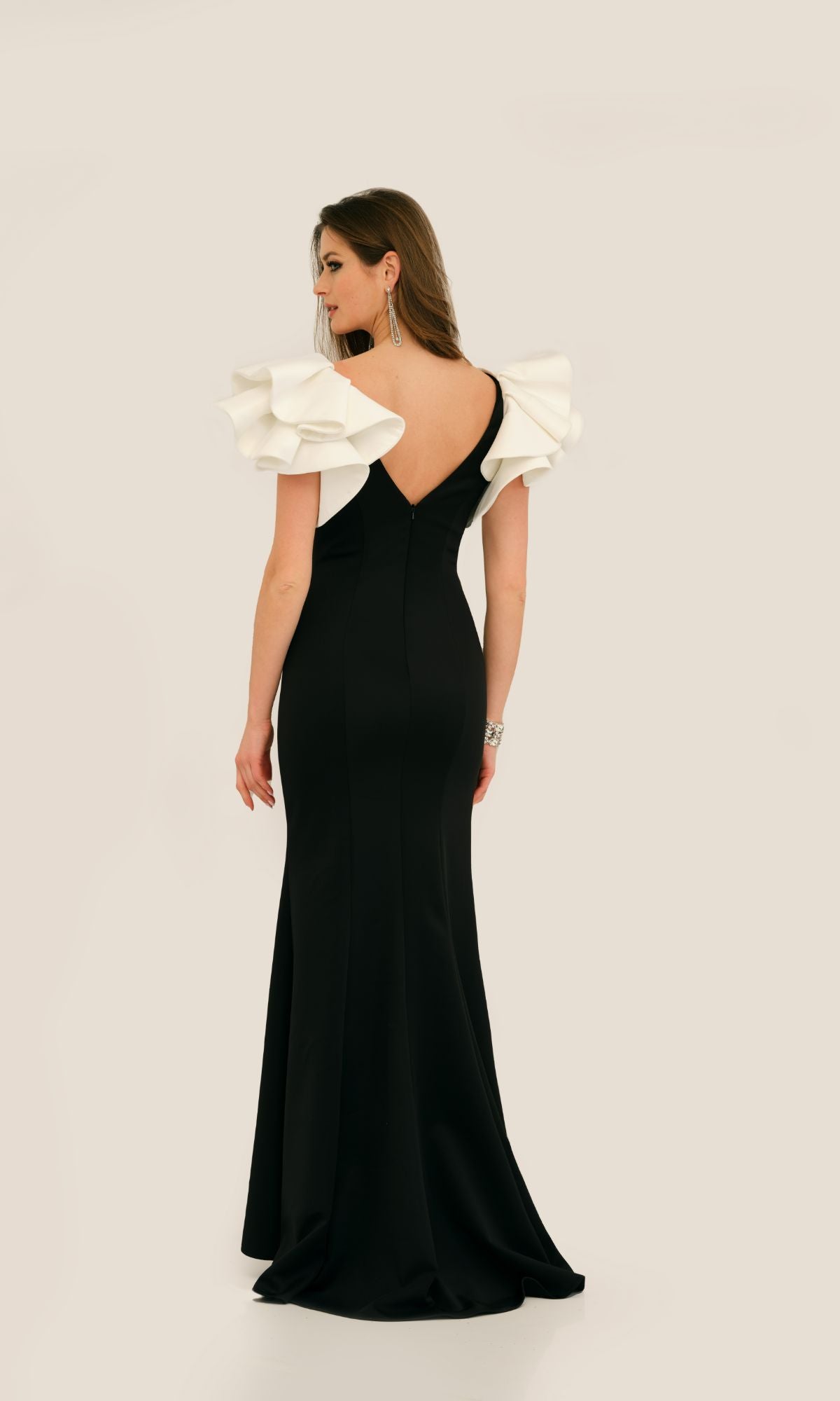 Woman in the Dave & Johnny 11314 Ruffle-Shoulder Prom Dress, featuring white ruffled shoulder details, standing and facing away against a plain light background.